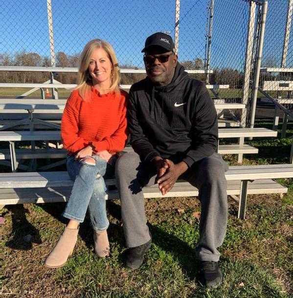 Two people sit next to each other on a set of bleachers on a sunny day.