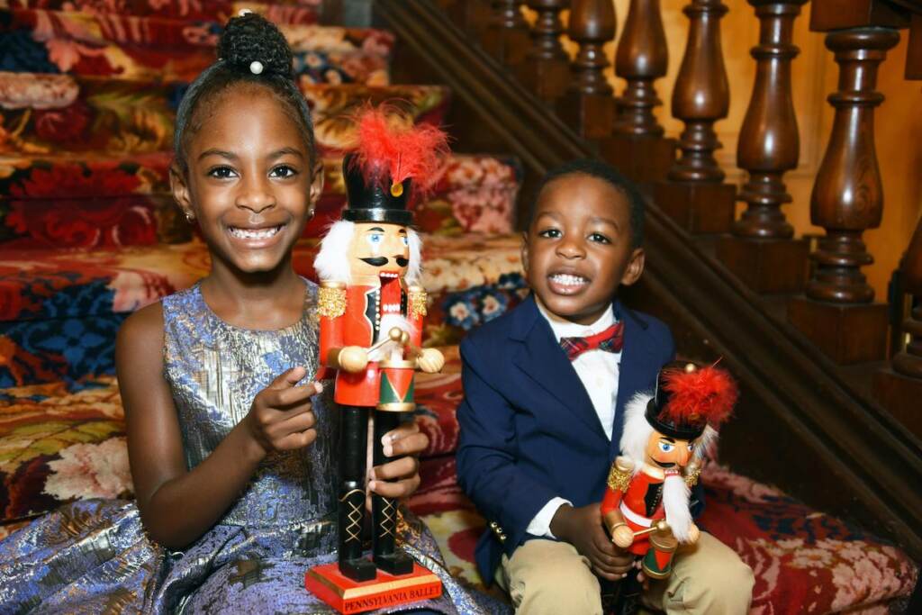 Two children smile and hold nutcracker figurines.