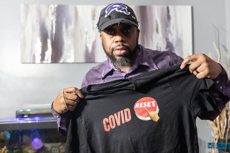 George Mink Jr. shows his COVID Reset t-shirt at his home in Delaware County, Pa