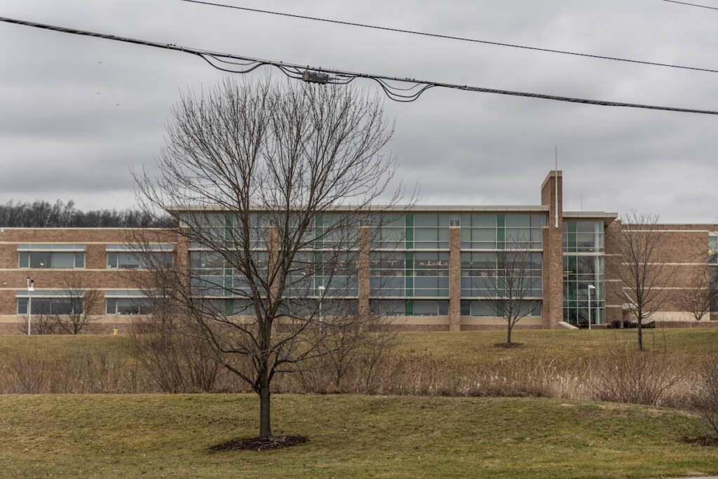 A school building is visible on a cloudy day.