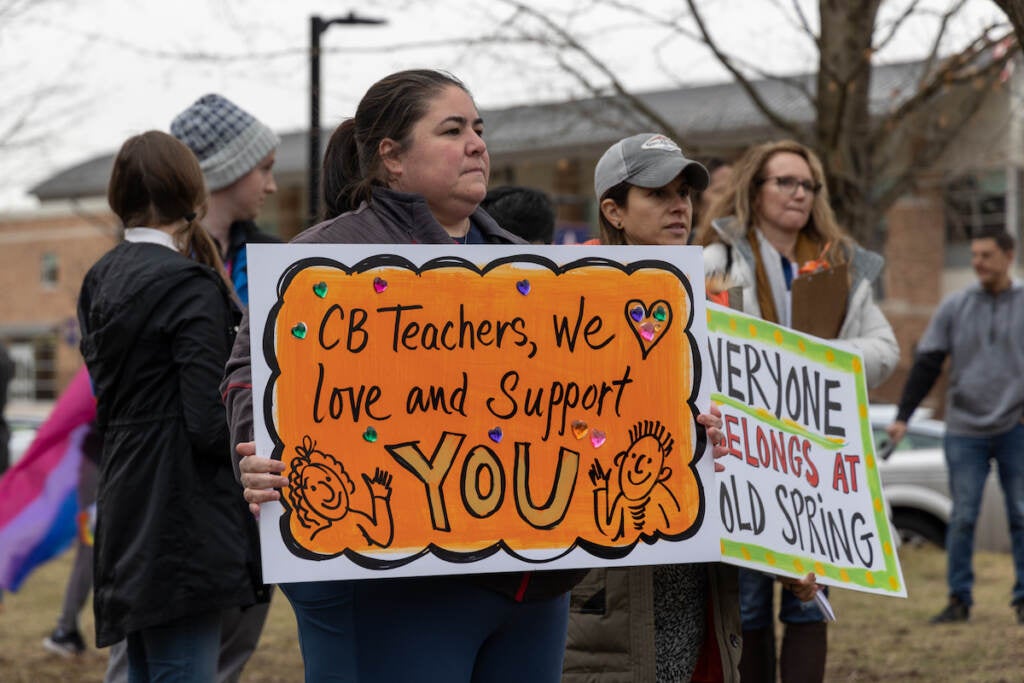 A person holds a sign that reads, "CB Teachers, we love and support you."