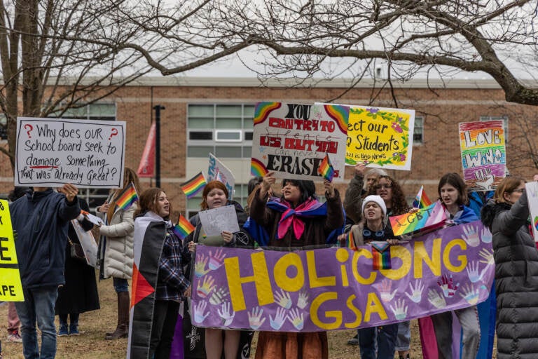 A group of students hold up a sign that reads 