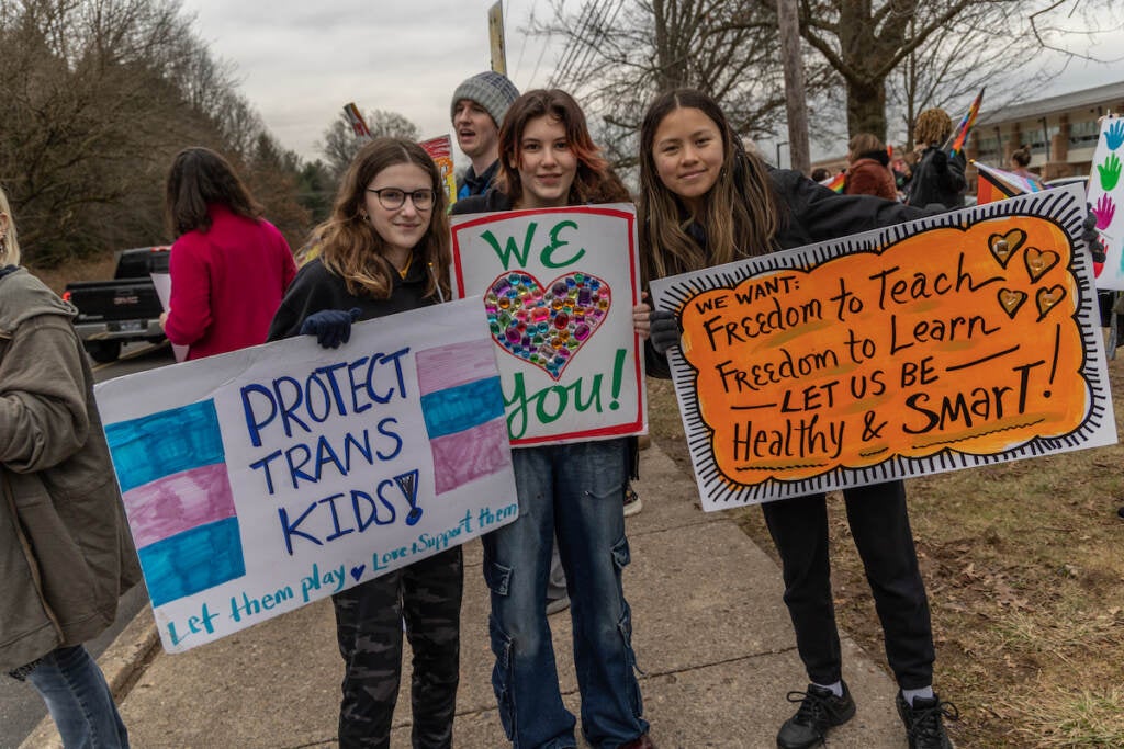 A group of students hold up signs supporting trans and LGBTQ students.