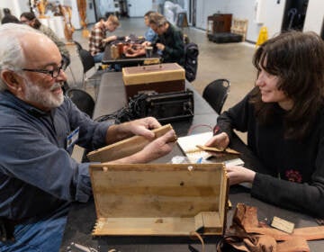 A volunteer (left) helps Leigh Hilford fix a sewing machine