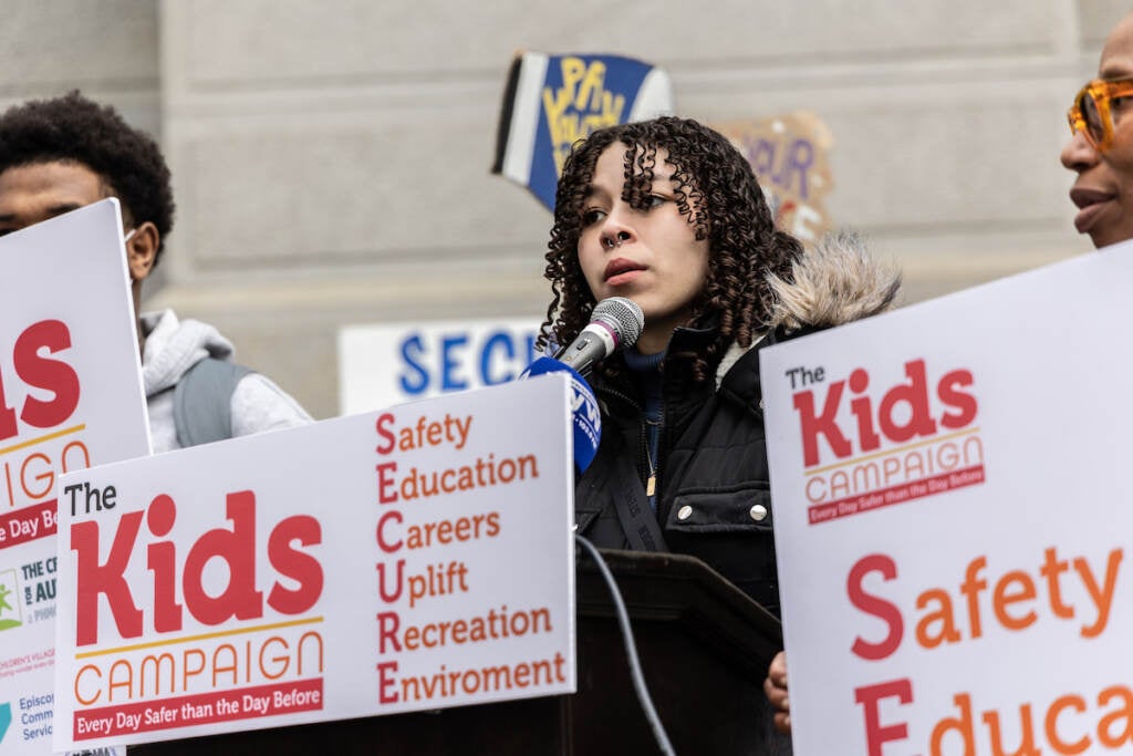 A student speaks into a microphone at a podium.