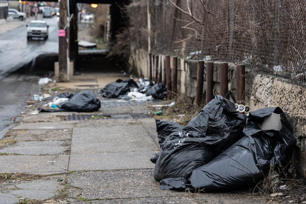 Bags of trash are visible on the sidewalk.