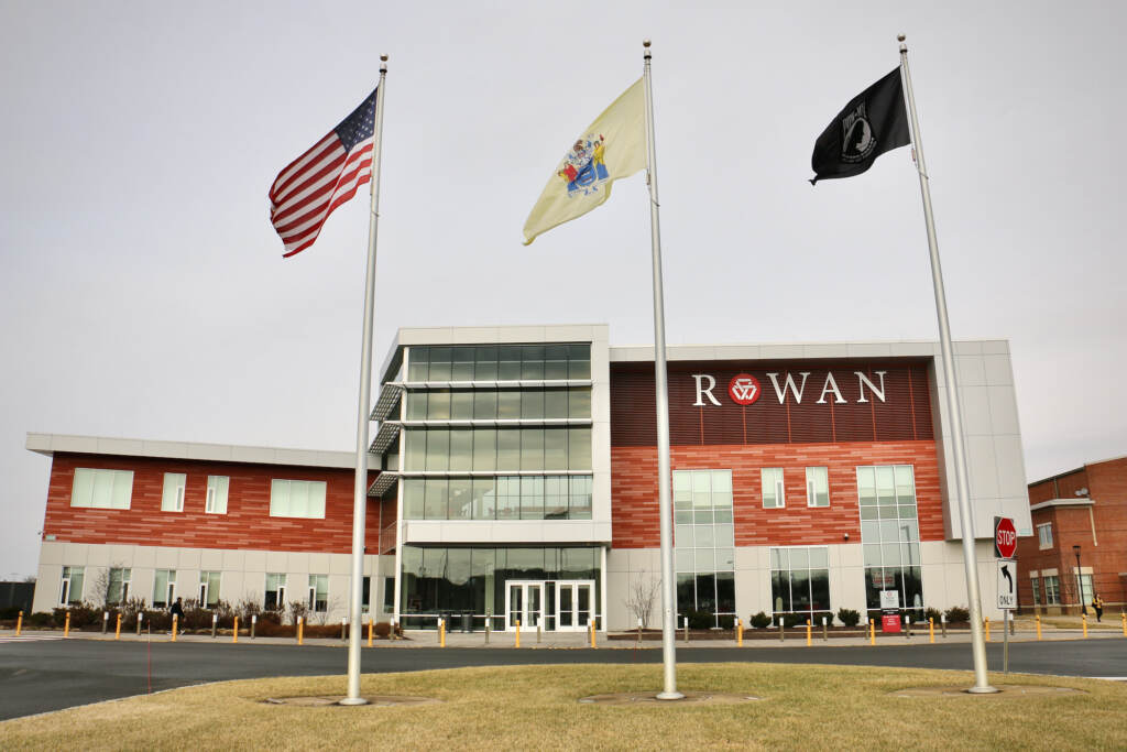 A college building with the word "Rowan" on it is visible. Three flags stand in front of the building.