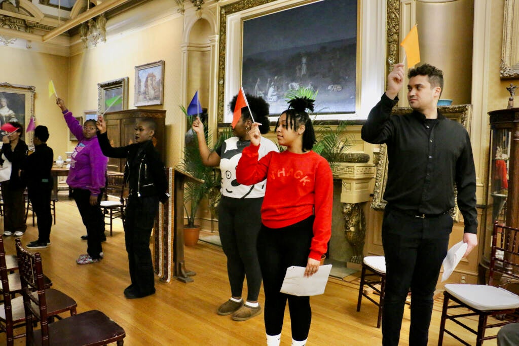 People stand in a room, waving small flags of different colors.