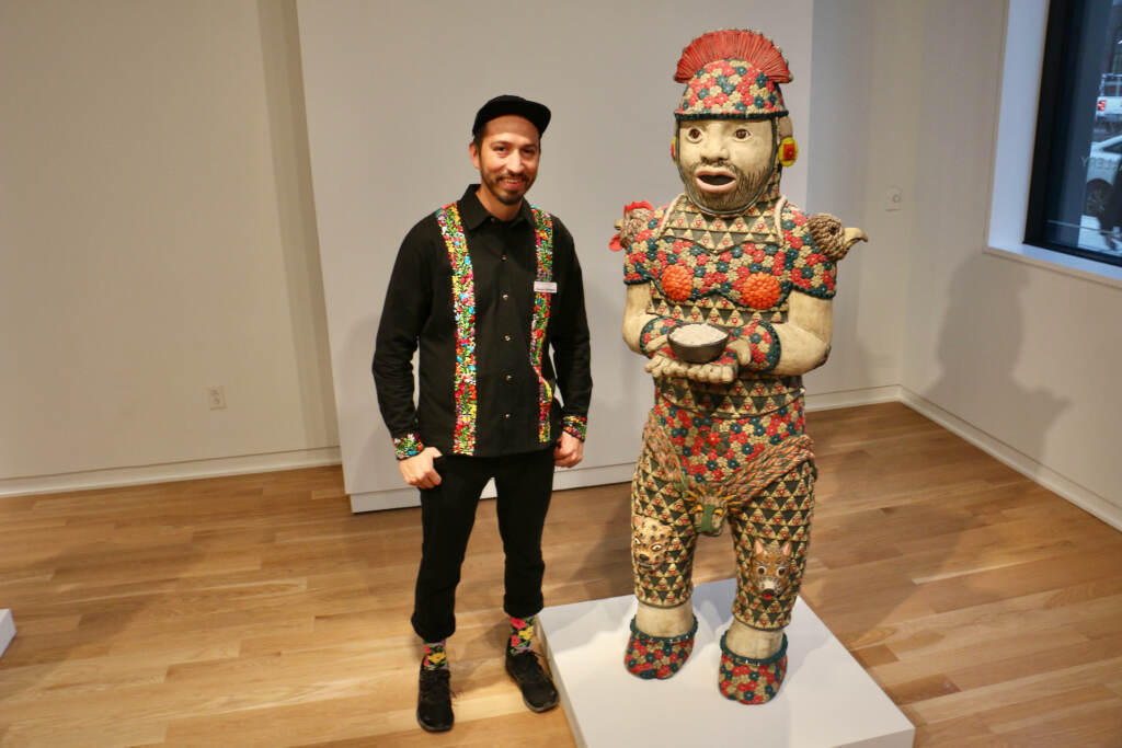 A sculptor stands next to his large-scale sculpture.