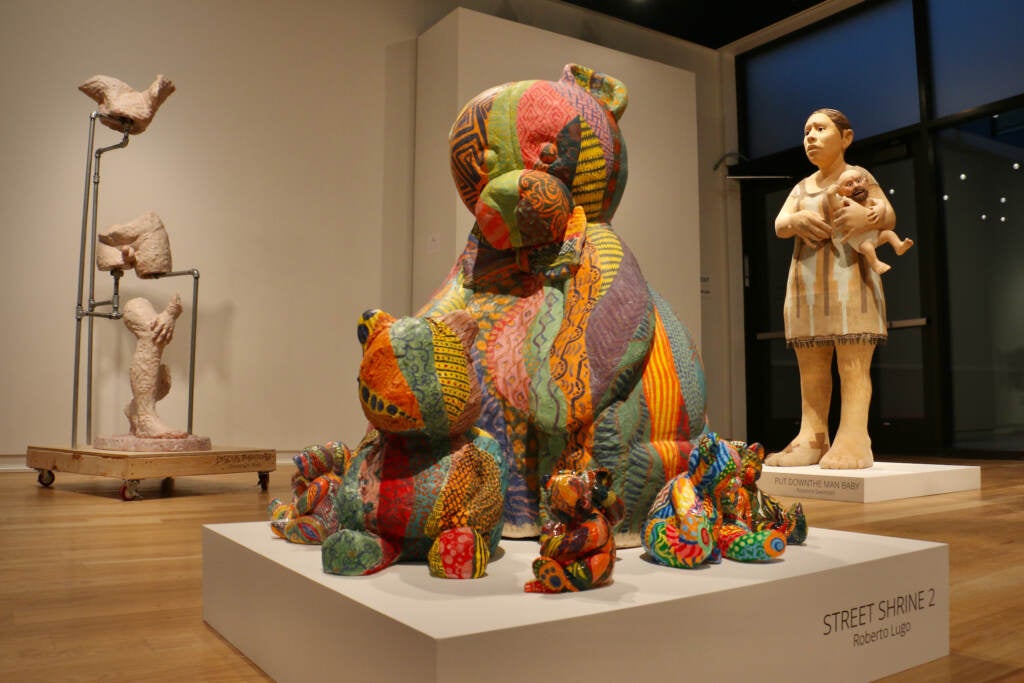 Several rainbow-colored sculpted teddy bears are on display.