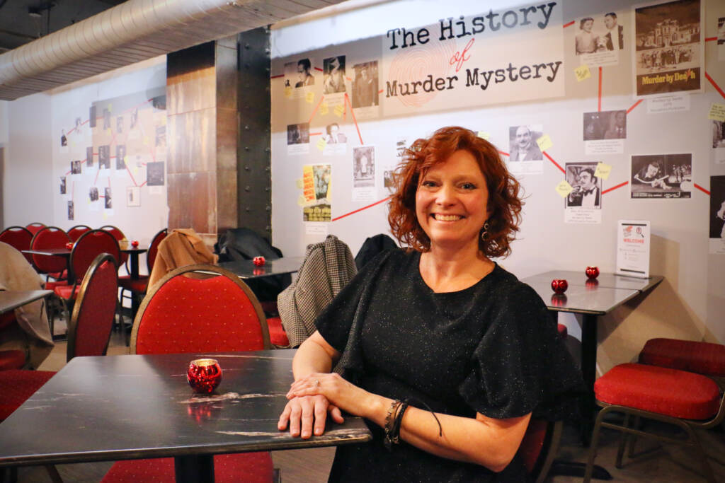 A woman sits at a table and poses for a photo.