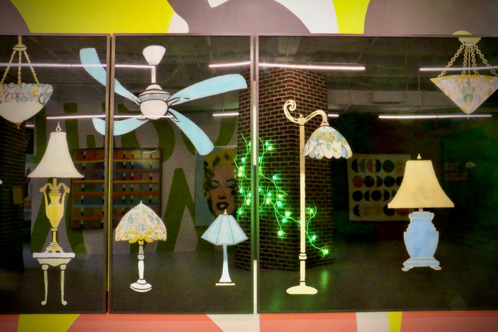 A painting shows a series of lamps and reflects the rest of the room in front of it.