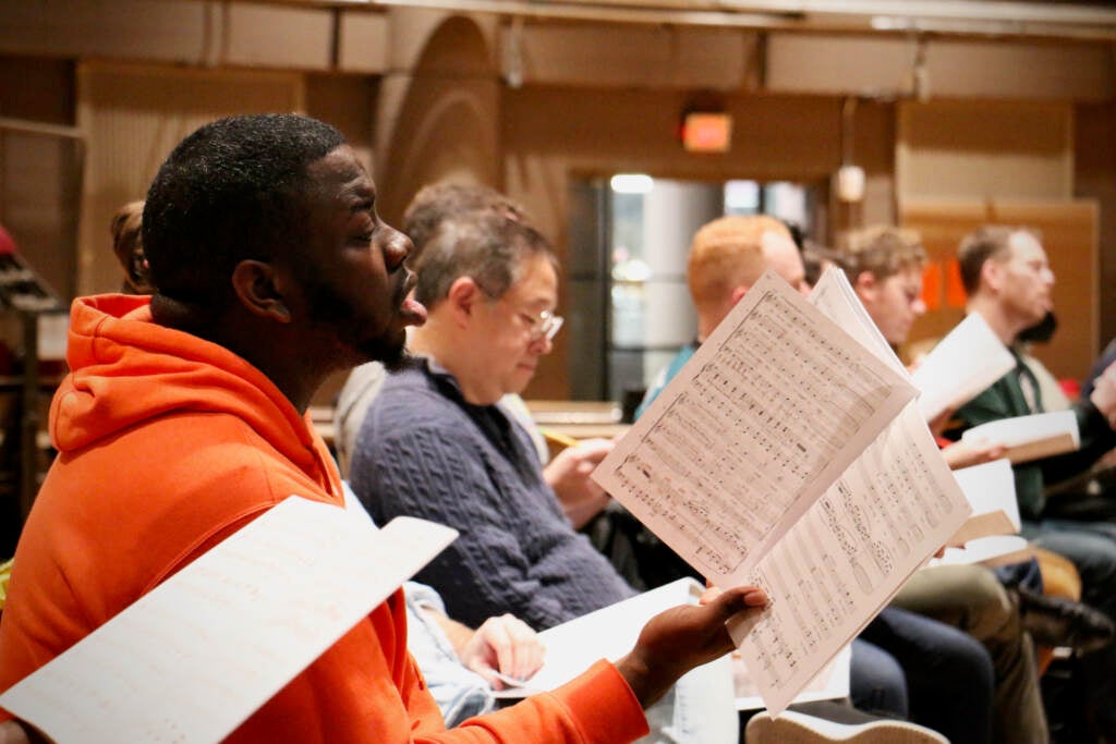 A close-up of a man in a chorus singing.