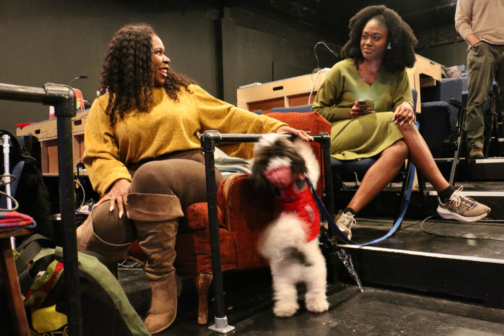 Two women talk in the seats of a theatre.