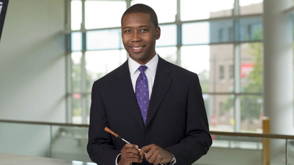 Rollo Dilworth poses for the camera, holding a conductor's wand.