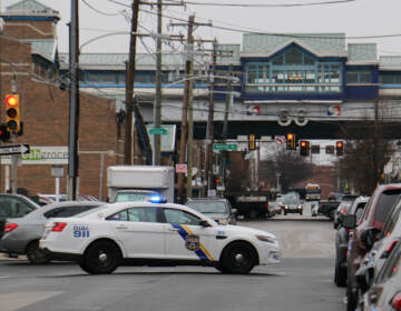 A police car is in the foreground. The El is visible in the background.