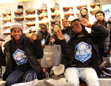 Kids pose for a photo, holding up the peace sign. Sneakers are visible in the background.