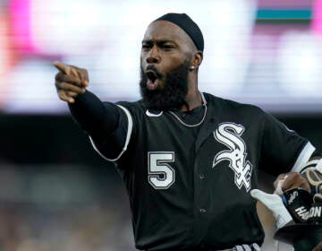 Chicago White Sox's Josh Harrison jokes with players in the San Diego Padres dugout during the sixth inning of a baseball game