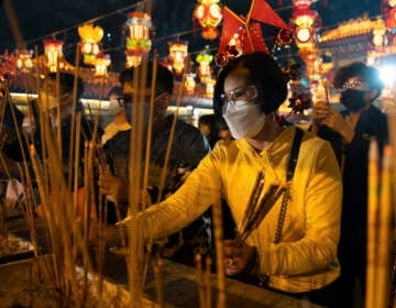 Worshippers wearing face masks burn their first joss sticks as they offer prayer at the Wong Tai Sin Temple, Saturday, Jan. 21, 2023, in Hong Kong