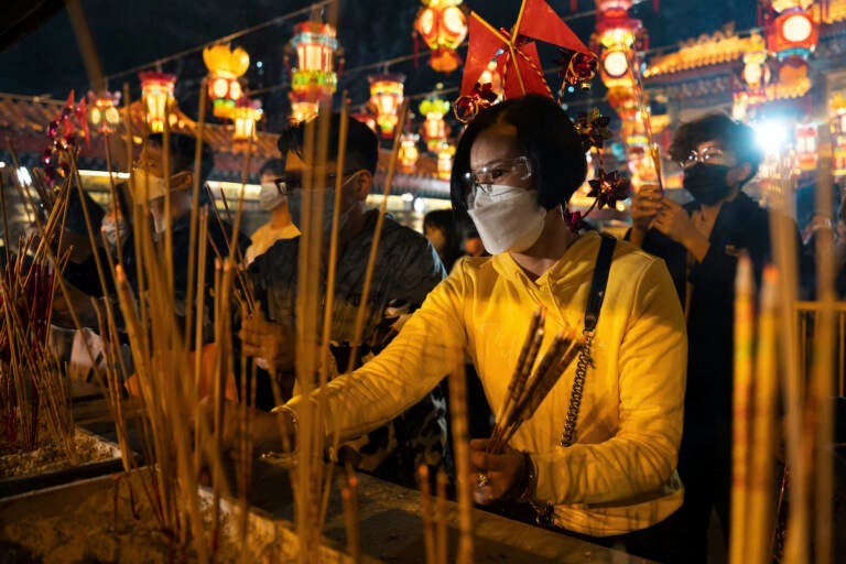 Worshippers wearing face masks burn their first joss sticks as they offer prayer at the Wong Tai Sin Temple, Saturday, Jan. 21, 2023, in Hong Kong