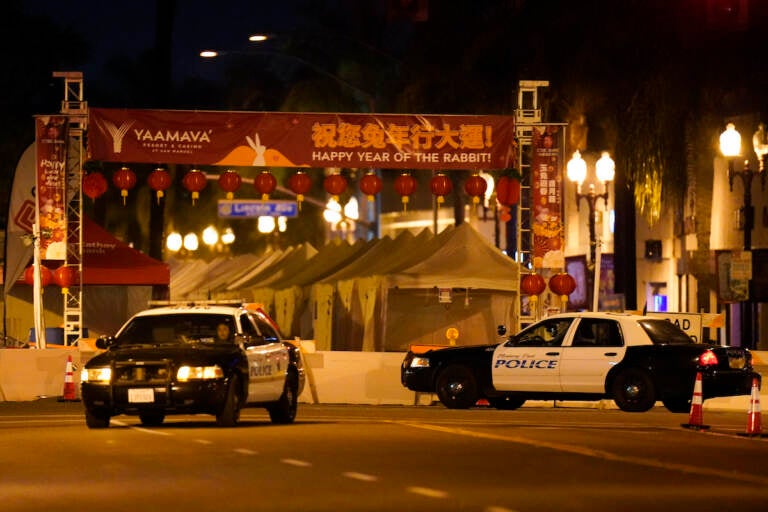 Two police vehicles are seen near a building where a shooting occurred in Monterey Park, Calif.