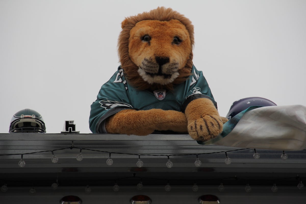 A stuffed lion dressed with a Philadelphia Eagles jersey is placed on the roof of a tailgate van