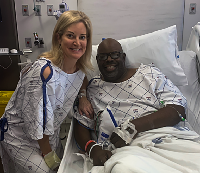 Molly Grayand Dan Napoleon, both wearing hospital gowns, pose together.