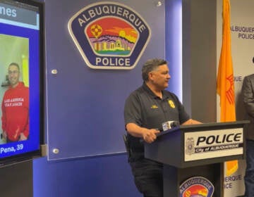 Albuquerque Police Chief Harold Medina speaks about the arrest of Solomon Peña, seen at left in an image projected onto a screen