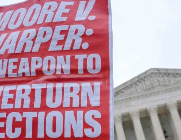 A Demonstrator holds a sign during a rally in front of the Supreme Court, Wednesday, Dec. 7, 2022, on Capitol Hill in Washington.
