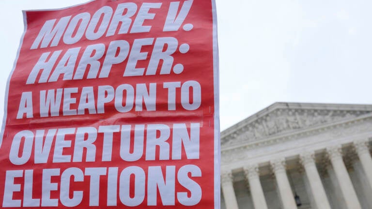 A Demonstrator holds a sign during a rally in front of the Supreme Court, Wednesday, Dec. 7, 2022, on Capitol Hill in Washington.