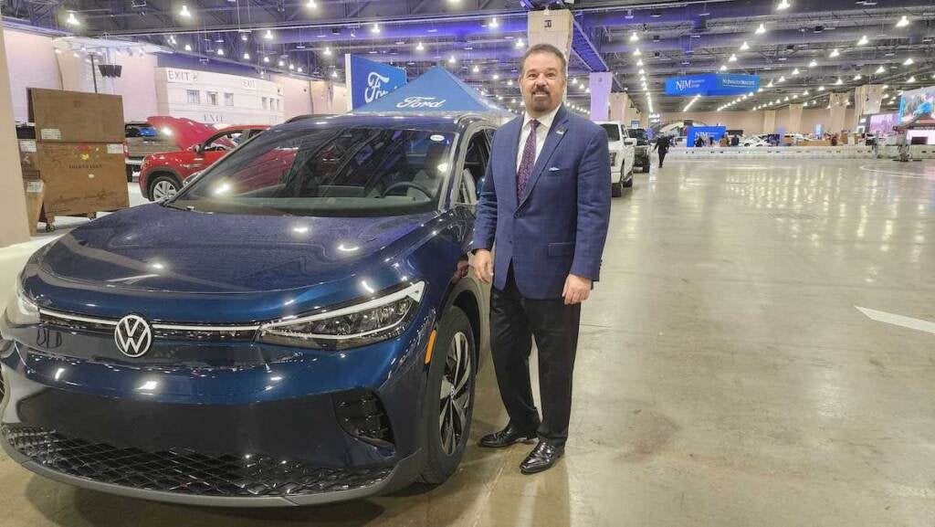 A man stands next to an electric vehicle.