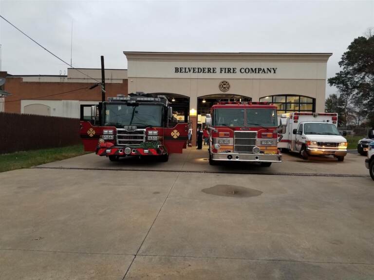 A wide shot of a fire station with fire trucks parked in front of it.