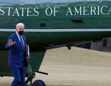 President Biden waves while walking towards a plane.