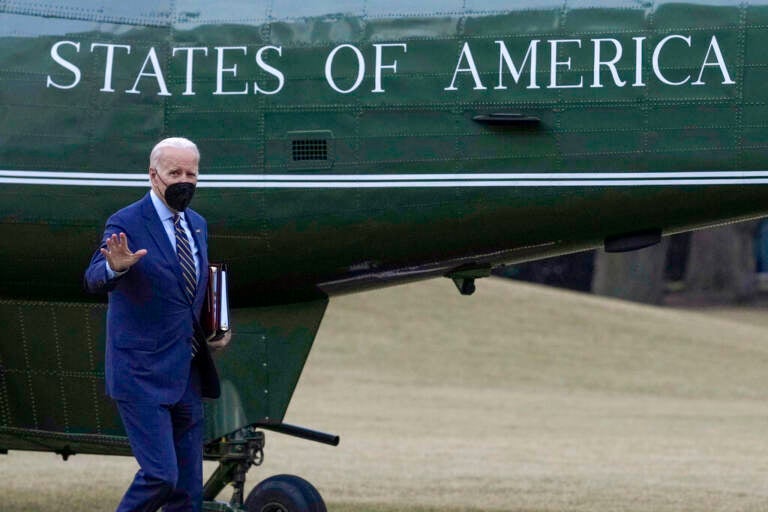 President Biden waves while walking towards a plane.