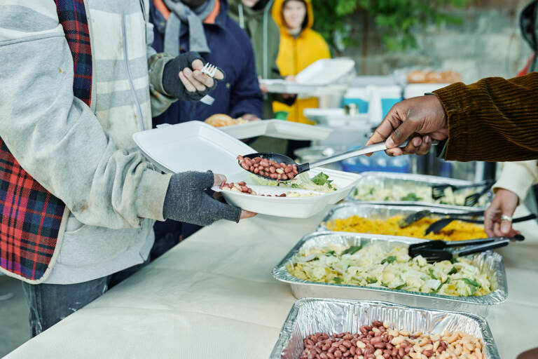 A person spoons food onto someone else's plate.