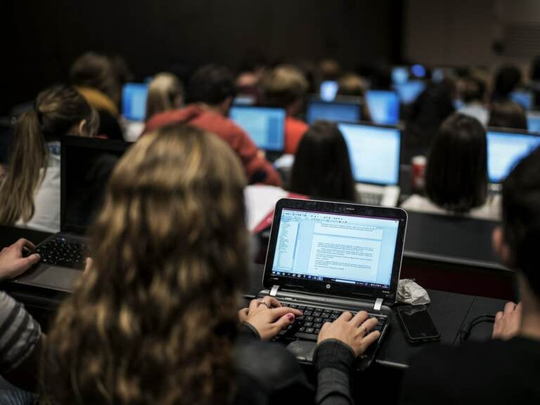 Students look at their laptops in a classroom.