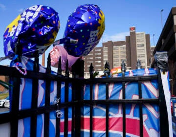 Ballons are displayed on a fence outside of a hospital building.