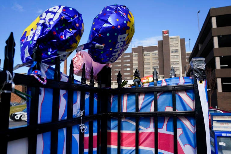 Ballons are displayed on a fence outside of a hospital building.