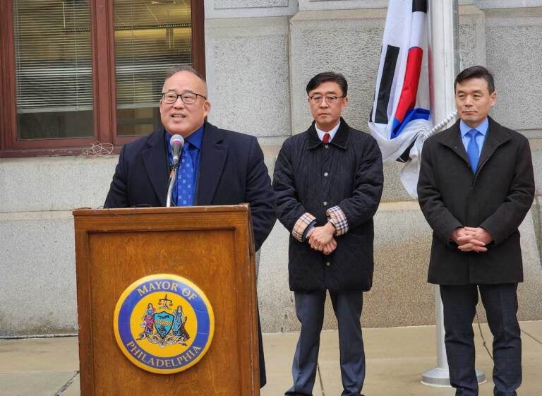 David Oh speaks at a podium outside of City Hall.