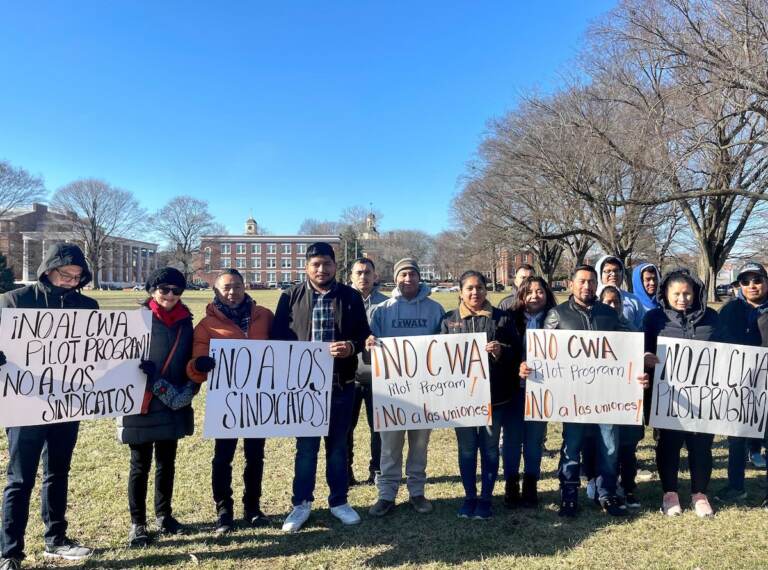 A group of people hold signs outside of the Delaware state legislature.