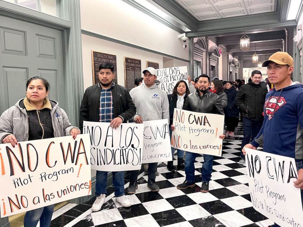 A group of people in a hallway hold signs.