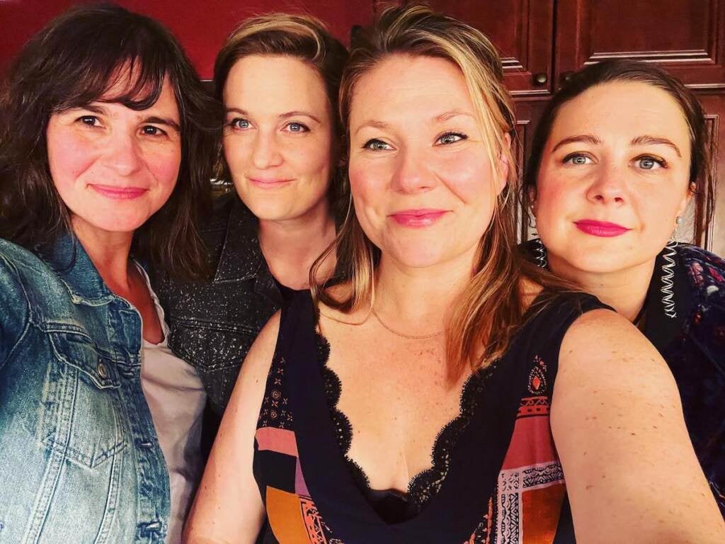 Four women smile into the camera as they pose for a photo.