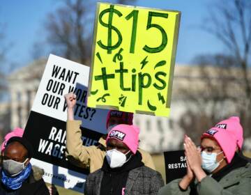 A person holds up a sign that reads