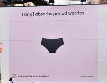 A photo of a large ad on a wall that has a light pink background and a picture of a pair of underwear along with the writing 