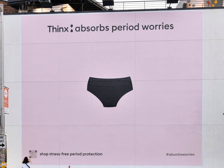 A photo of a large ad on a wall that has a light pink background and a picture of a pair of underwear along with the writing 