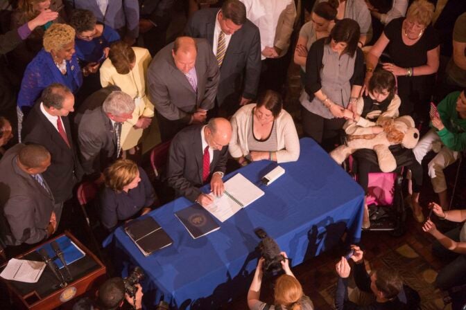 n overhead shot of former Pa. Gov Wolf signing legislation, surrounded by a group in Harrisburg