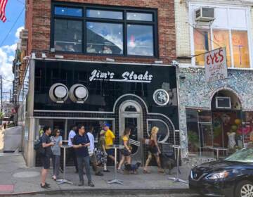 People gather around Jim's Steaks storefront.