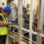 A student in Middle Bucks Institute of Technology's HVAC/plumbing program uses a mock-up to practice installing a network of plumbing pipes
