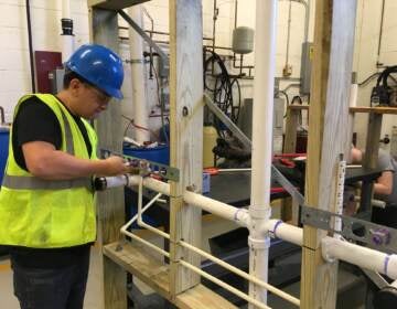 A student in Middle Bucks Institute of Technology's HVAC/plumbing program uses a mock-up to practice installing a network of plumbing pipes