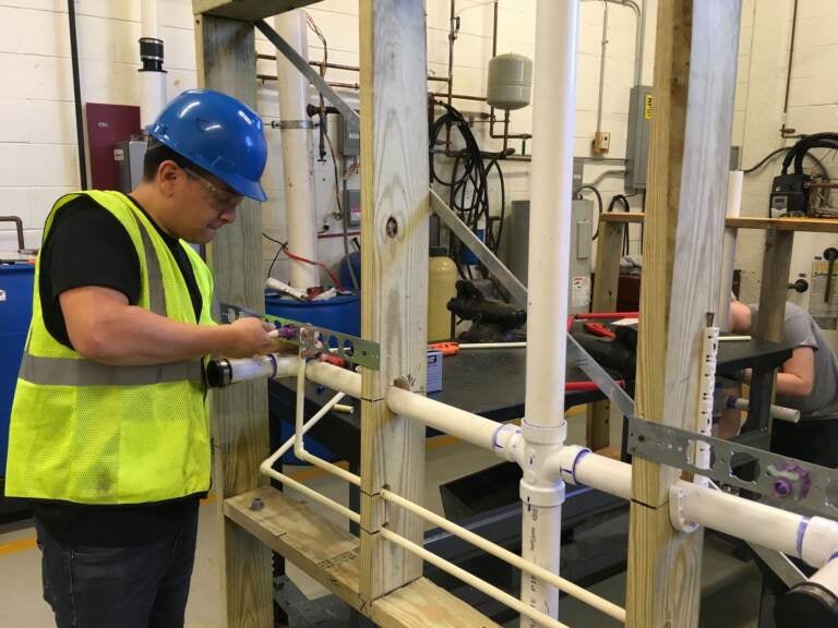 A student in Middle Bucks Institute of Technology's HVAC/plumbing program uses a mock-up to practice installing a network of plumbing pipes